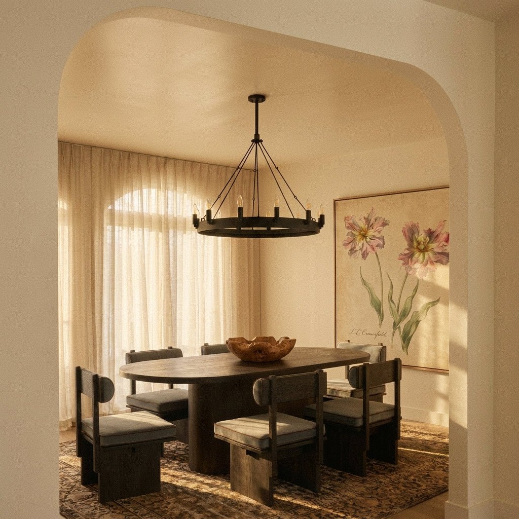 Clérachic matte black ring chandelier above an oval wooden dining table, lit by warm light through sheer curtains.