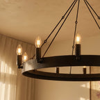 Close view of the Clérachic matte black ring chandelier with textured iron band, candle sleeves and filament bulbs glowing.