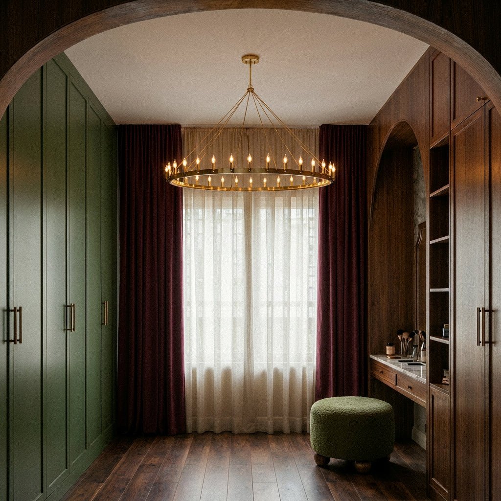 Clérachic brass ring chandelier glowing in a dressing room with green wardrobes, plum curtains and a boucle ottoman.