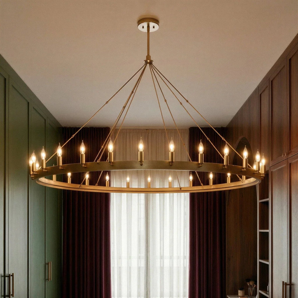 Clérachic large brass ring chandelier lit in a dressing room, its candle-style bulbs ringing the band against dark curtains.