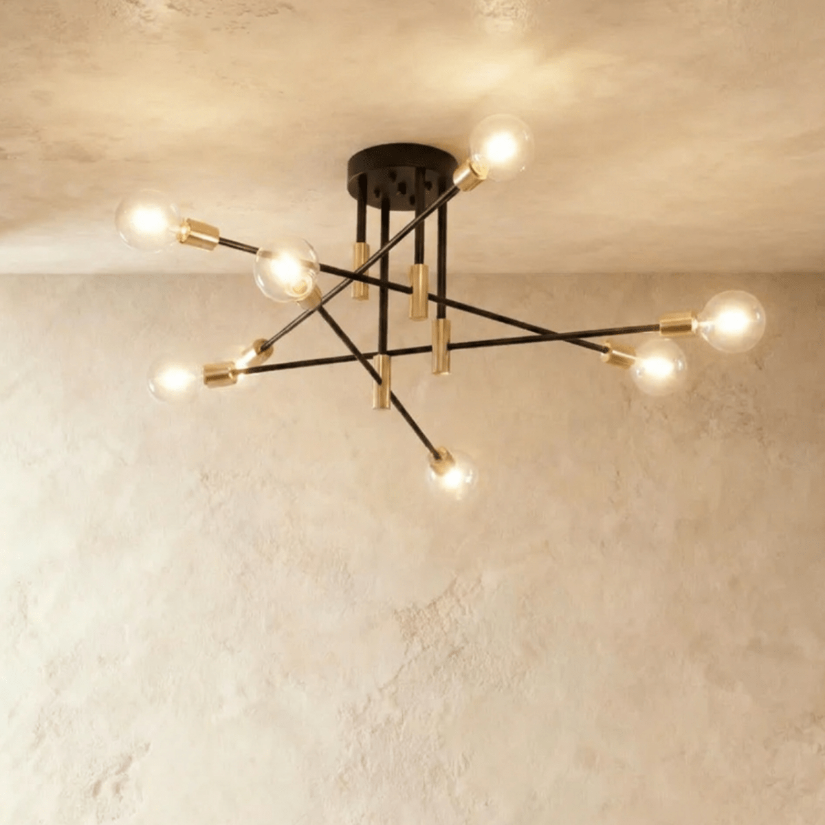 Clérachic 8-arm iron ring chandelier in black with brass sockets, clear filament bulbs lit against a plaster ceiling.