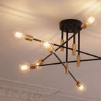 Clérachic 8-arm iron ring chandelier in black with brass sockets, clear filament bulbs lit beneath ornate crown molding.