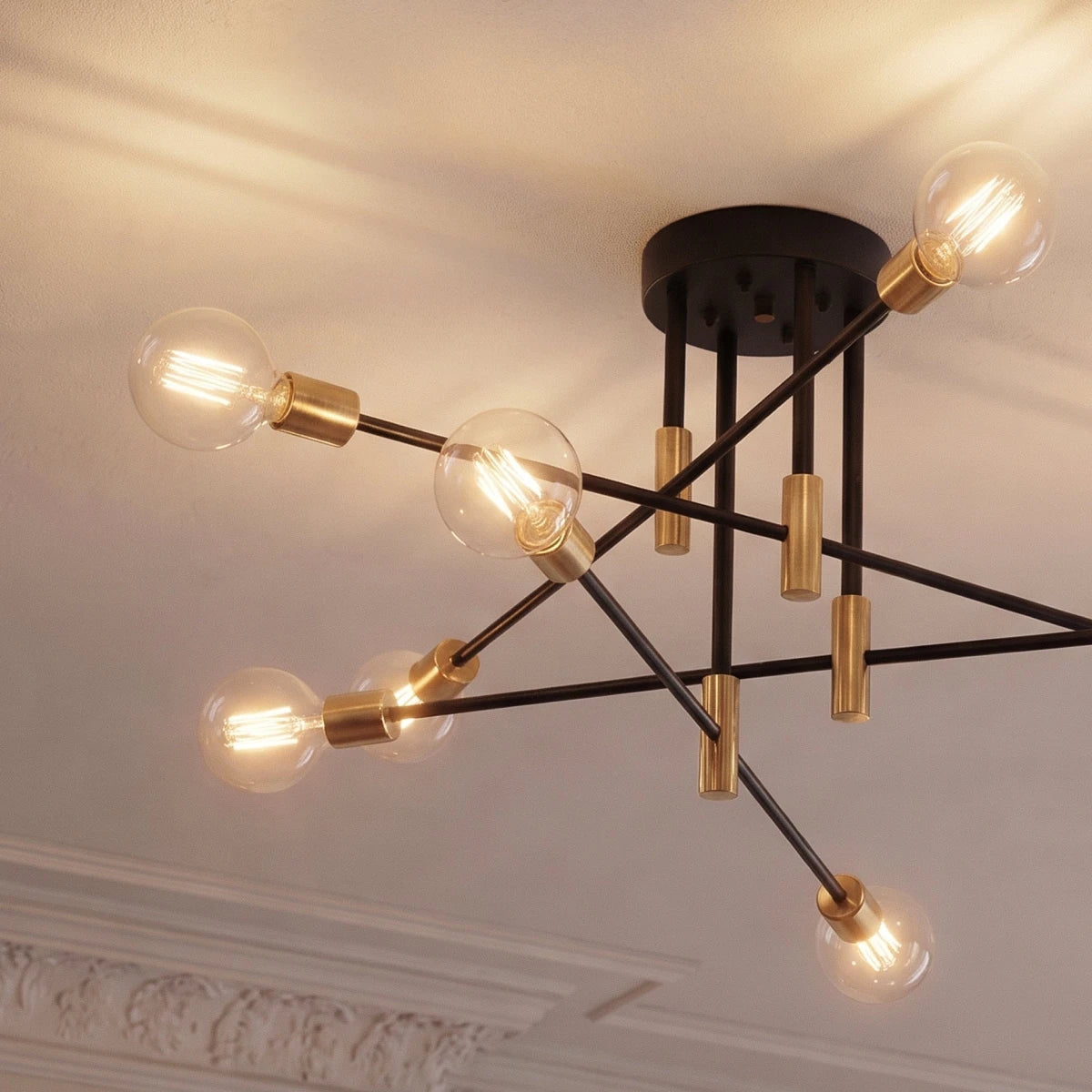 Clérachic 8-arm iron ring chandelier in black with brass sockets, clear filament bulbs lit beneath ornate crown molding.