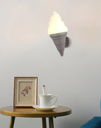 Grey-coned Clérachic wall light lit warm white above a round brass side table holding a framed print and a teacup.