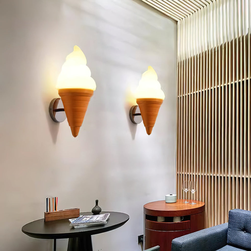 Two orange-coned Clérachic wall lights lit on a tall pale wall, above a round black table and a blue sofa, with a slatted wood panel beside them.