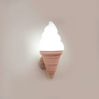 Pink-coned Clérachic wall light lit in cool white against a pale mauve wall, with the swirl shade bright above the ribbed cone.