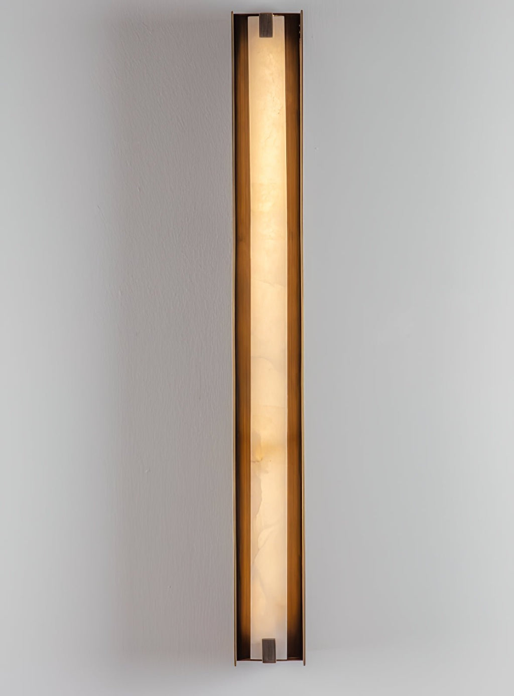 Clérachic Isolde at full height on a white wall, a slim ribbon of warm light held in bronze.
