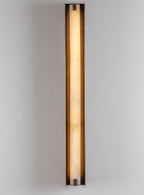 Clérachic Isolde at full height on a white wall, a slim ribbon of warm light held in bronze.