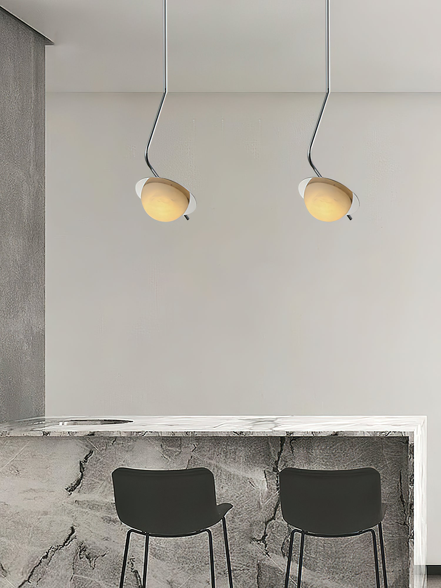 Clérachic Ivvaros pendants hung in a pair above a stone breakfast bar set with two black stools.