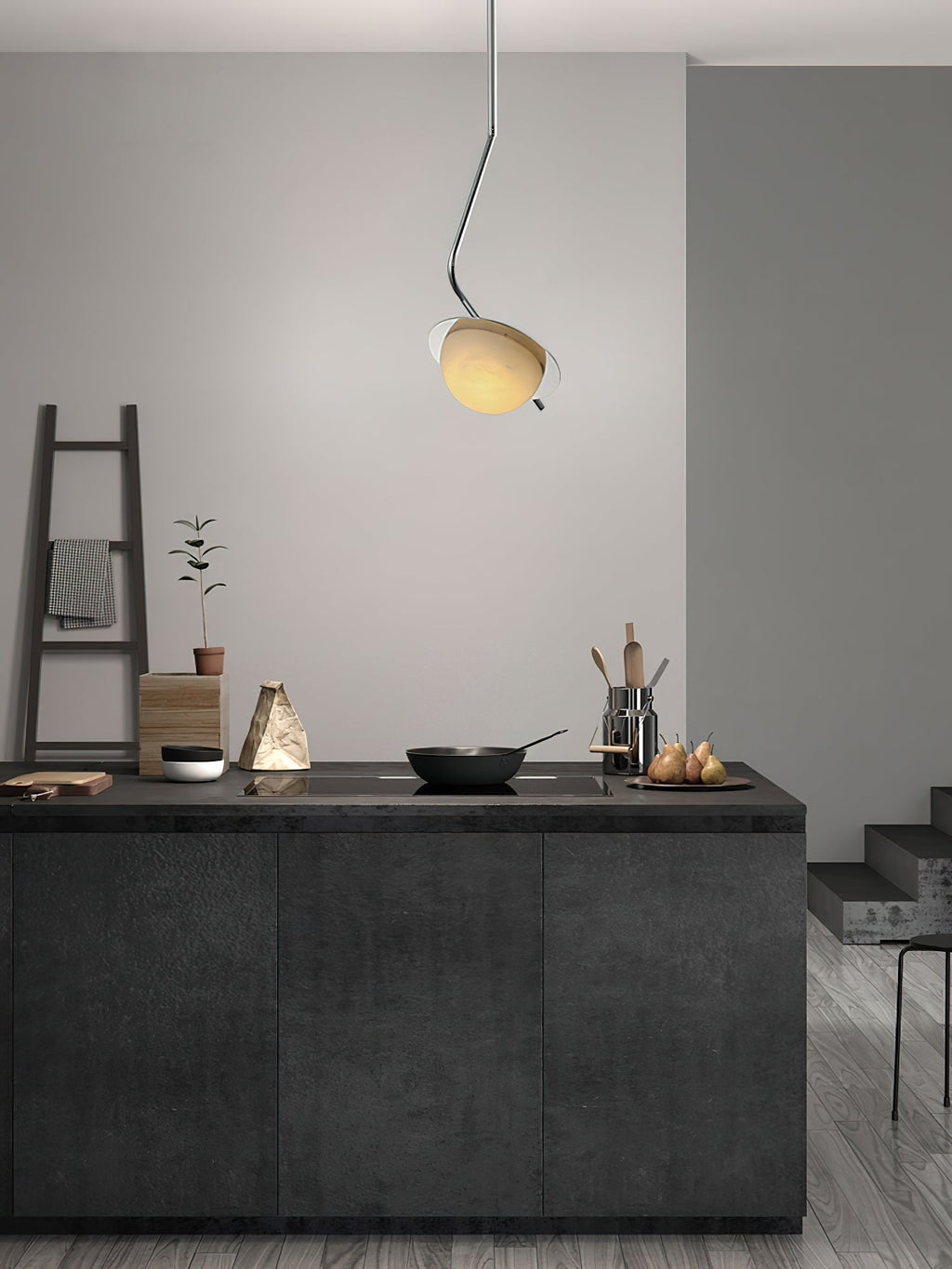 The Clérachic Ivvaros pendant over a dark kitchen island, its small shade lit warm against a pale wall.