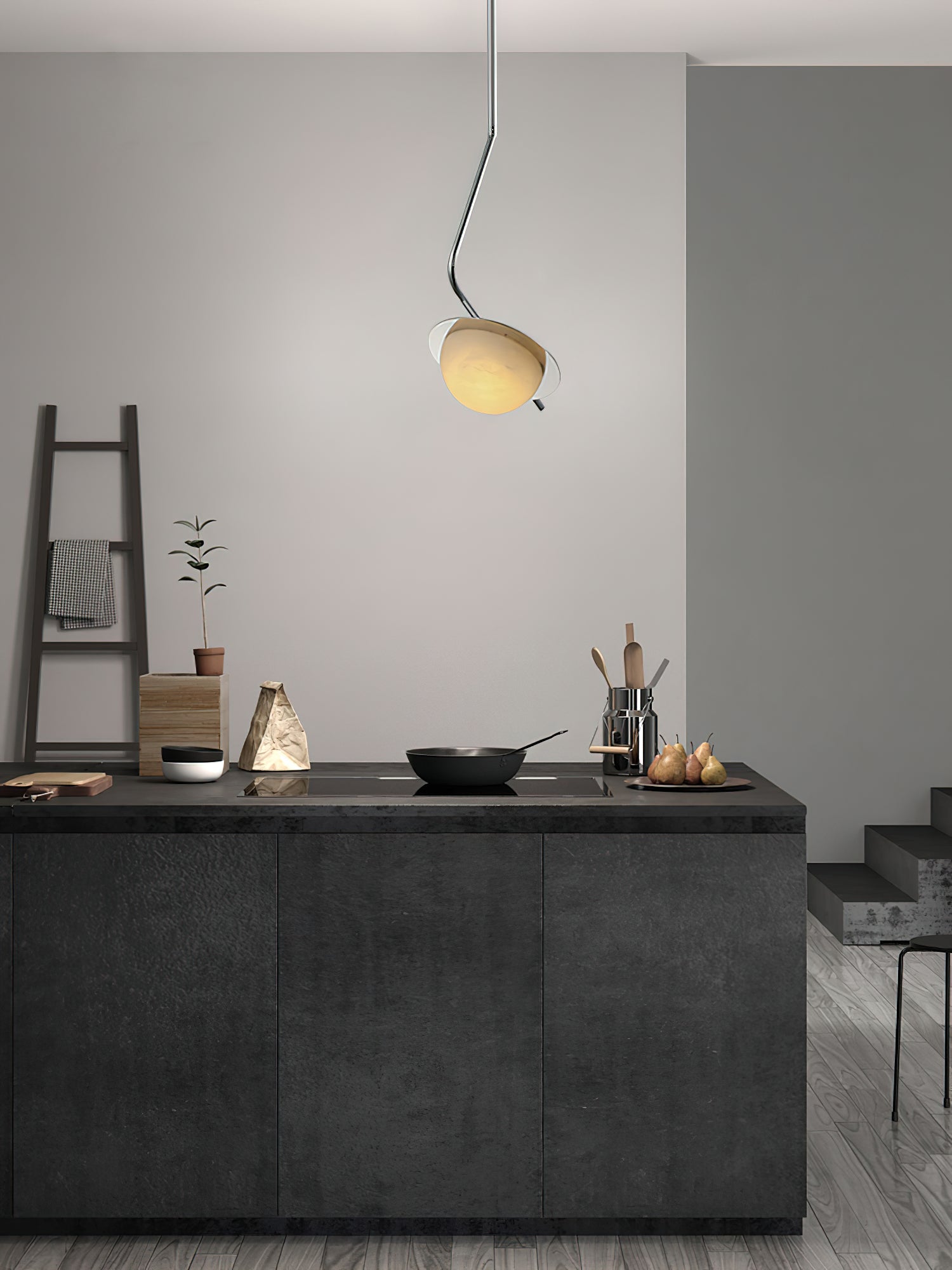 The Clérachic Ivvaros pendant over a dark kitchen island, its small shade lit warm against a pale wall.