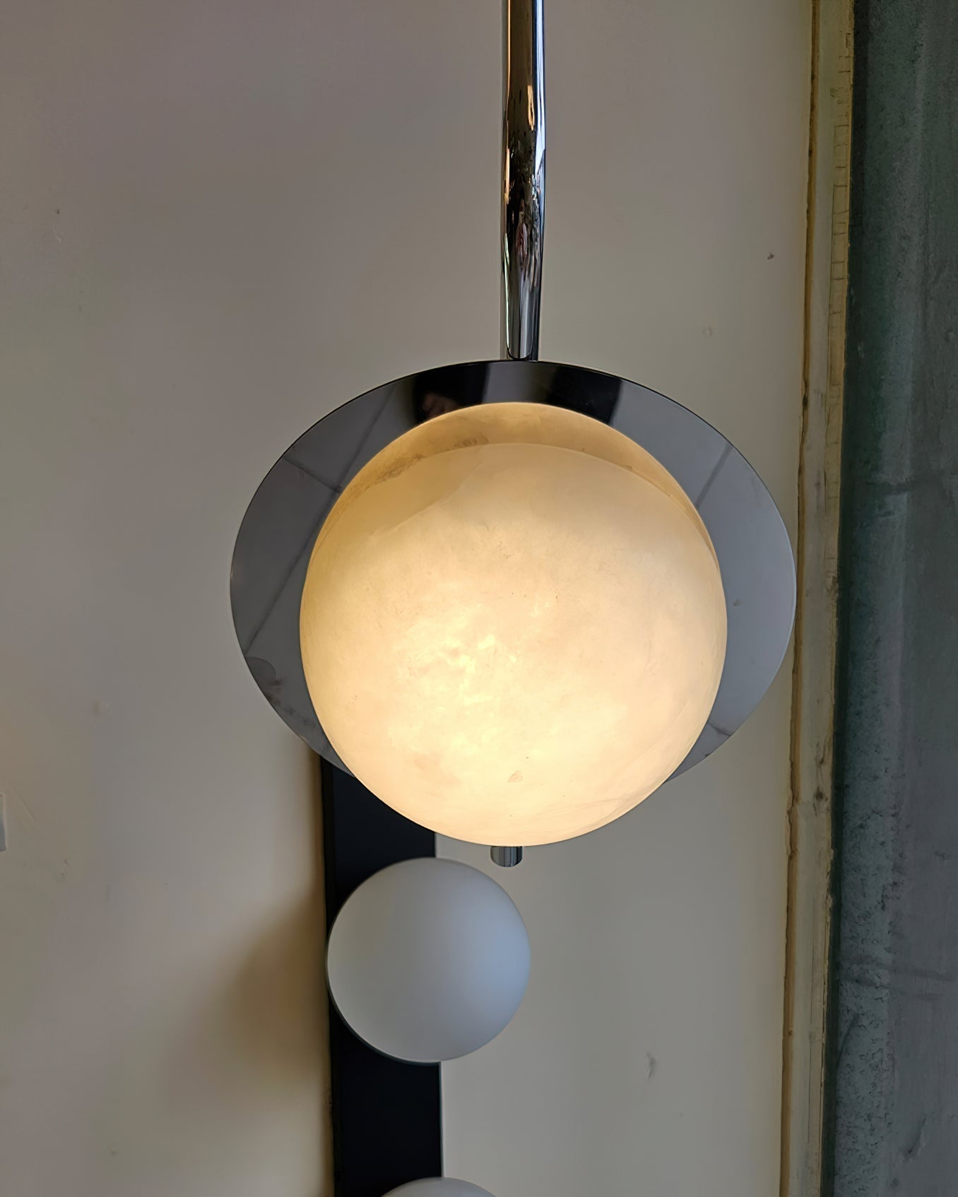 Clérachic Ivvaros lit close up, the alabaster dome glowing warm amber inside its polished chrome cup.