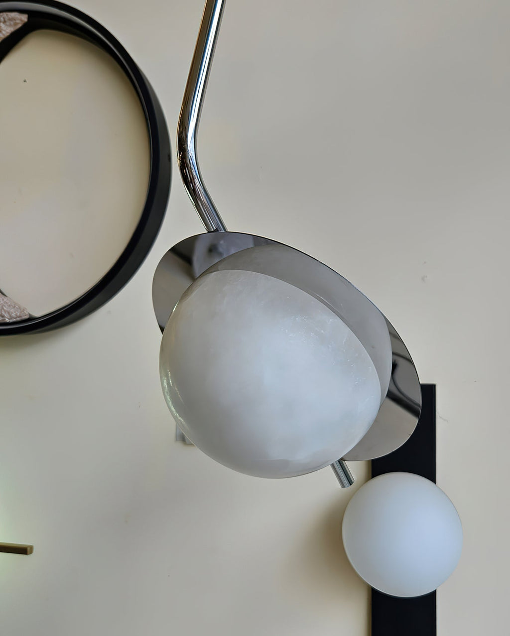 The Clérachic Ivvaros pendant unlit, its pale alabaster dome reading as matte stone beside a round mirror.
