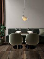 Clérachic Ivvaros pendant above a dining nook, dropped low over a green velvet banquette and laid table.