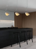 Clérachic Ivvaros pendants in a run of three above a black bar, walnut panelling behind them.