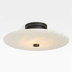 The Clérachic black-finish flush mount shown broadside, its shallow alabaster dome curving down to a dark stud.