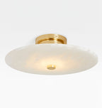 Clérachic brass flush mount close in, warm light pooling through the stone toward the polished centre cap.