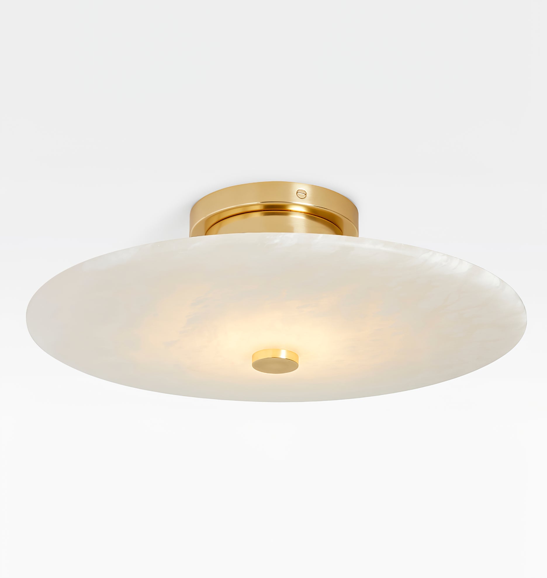Clérachic brass flush mount close in, warm light pooling through the stone toward the polished centre cap.