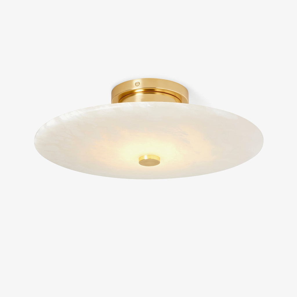 The Clérachic brass version from below, its lit alabaster disc reading softly cream right across the face.
