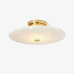 The Clérachic brass version from below, its lit alabaster disc reading softly cream right across the face.