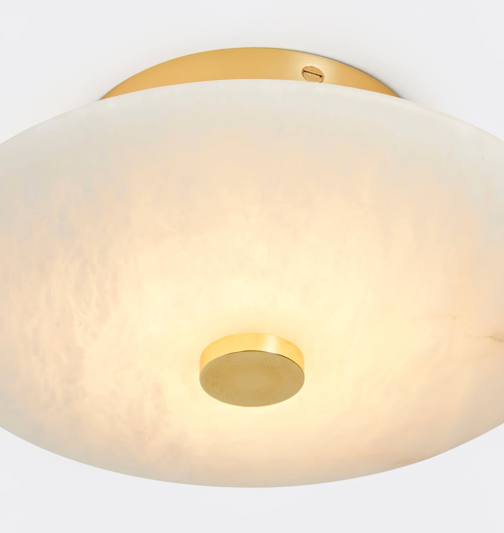 The Clérachic brass canopy and lit shade in close crop, warm metal against the cream tone of the stone.