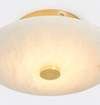 The Clérachic brass canopy and lit shade in close crop, warm metal against the cream tone of the stone.