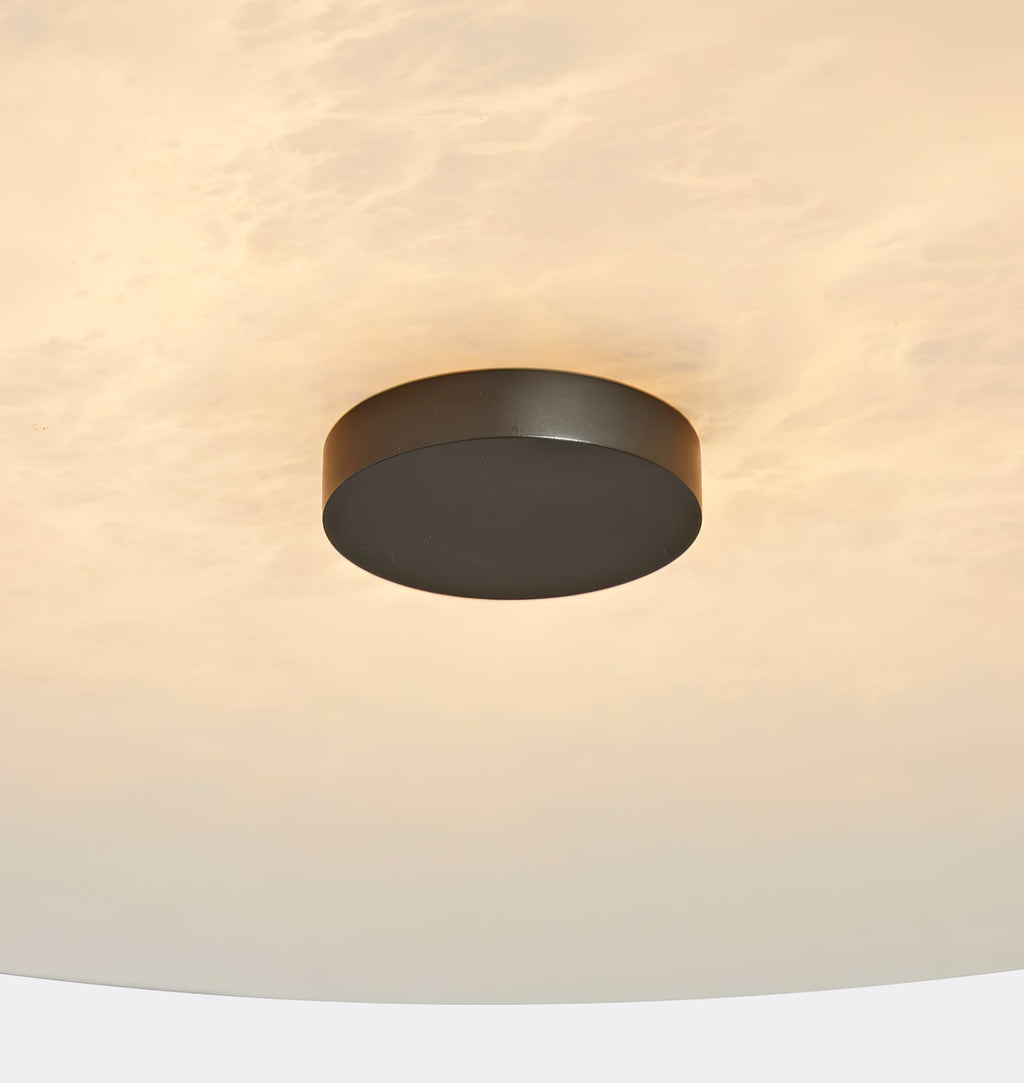 Clérachic alabaster up close, a black centre cap set into softly glowing, cloud-patterned natural stone.