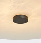 Clérachic alabaster up close, a black centre cap set into softly glowing, cloud-patterned natural stone.