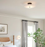 The Clérachic black-finish light on a bedroom ceiling, with a second glowing softly by the curtained window.
