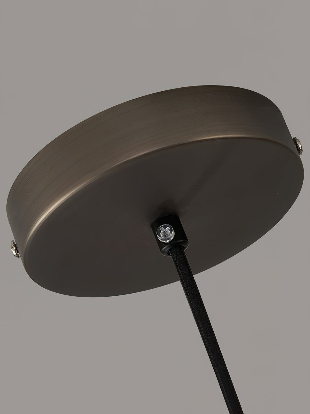 Close view of the round ceiling canopy on the Clérachic Jewel Pendant Light, with its fixing screws and black fabric cord.