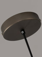 Close view of the round ceiling canopy on the Clérachic Jewel Pendant Light, with its fixing screws and black fabric cord.