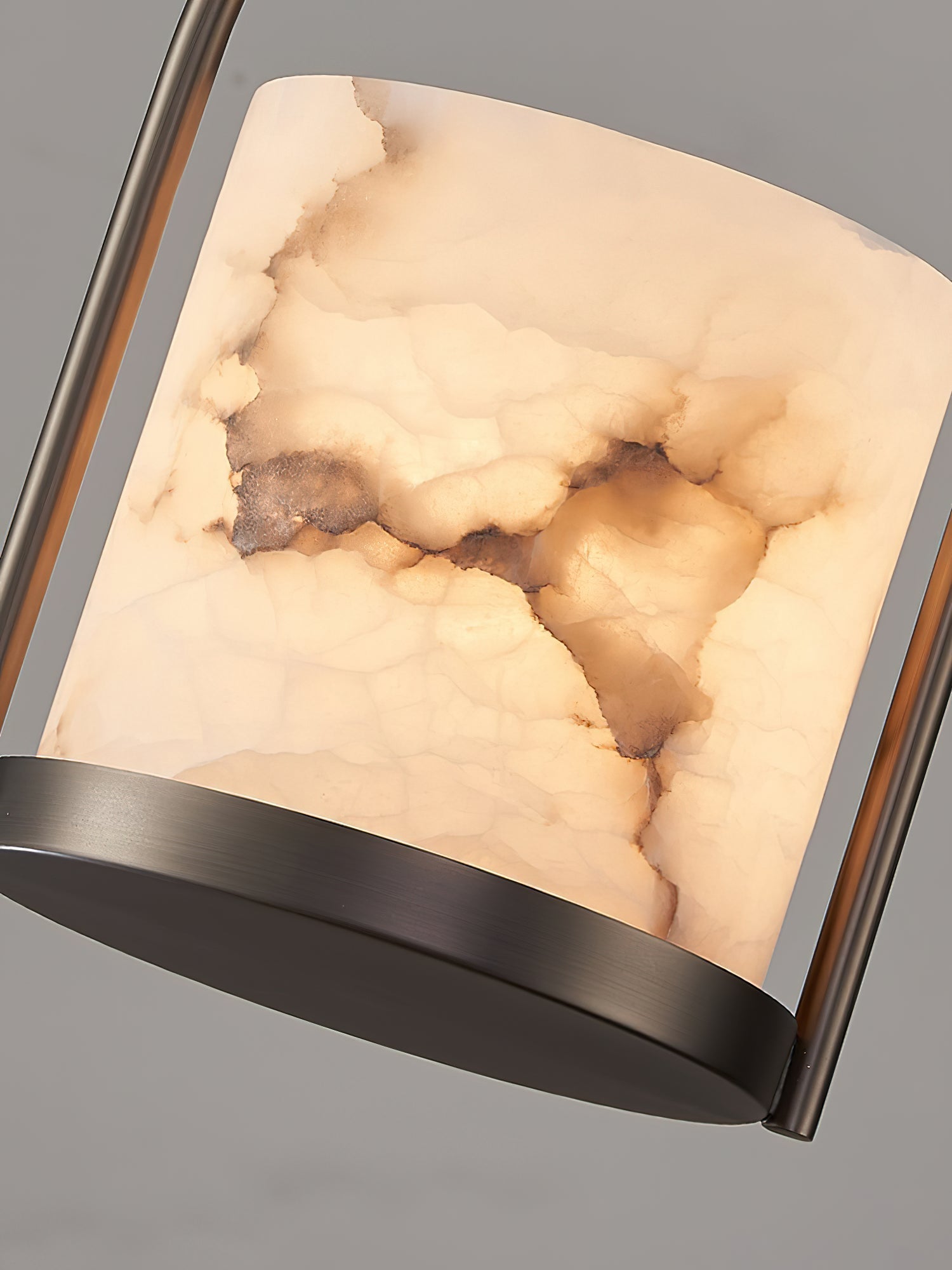 Detail of the Clérachic alabaster shade, warm veining running through the stone between the brass arch and the base disc.