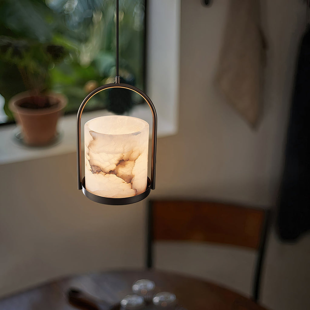 The Clérachic Jewel Pendant Light lit over a round dining table at dusk, beside a window and a potted plant.