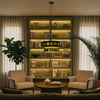 This Clérachic green glass pendant glows yellow-green at its waist, in front of lit shelves, with two armchairs and a round coffee table below.