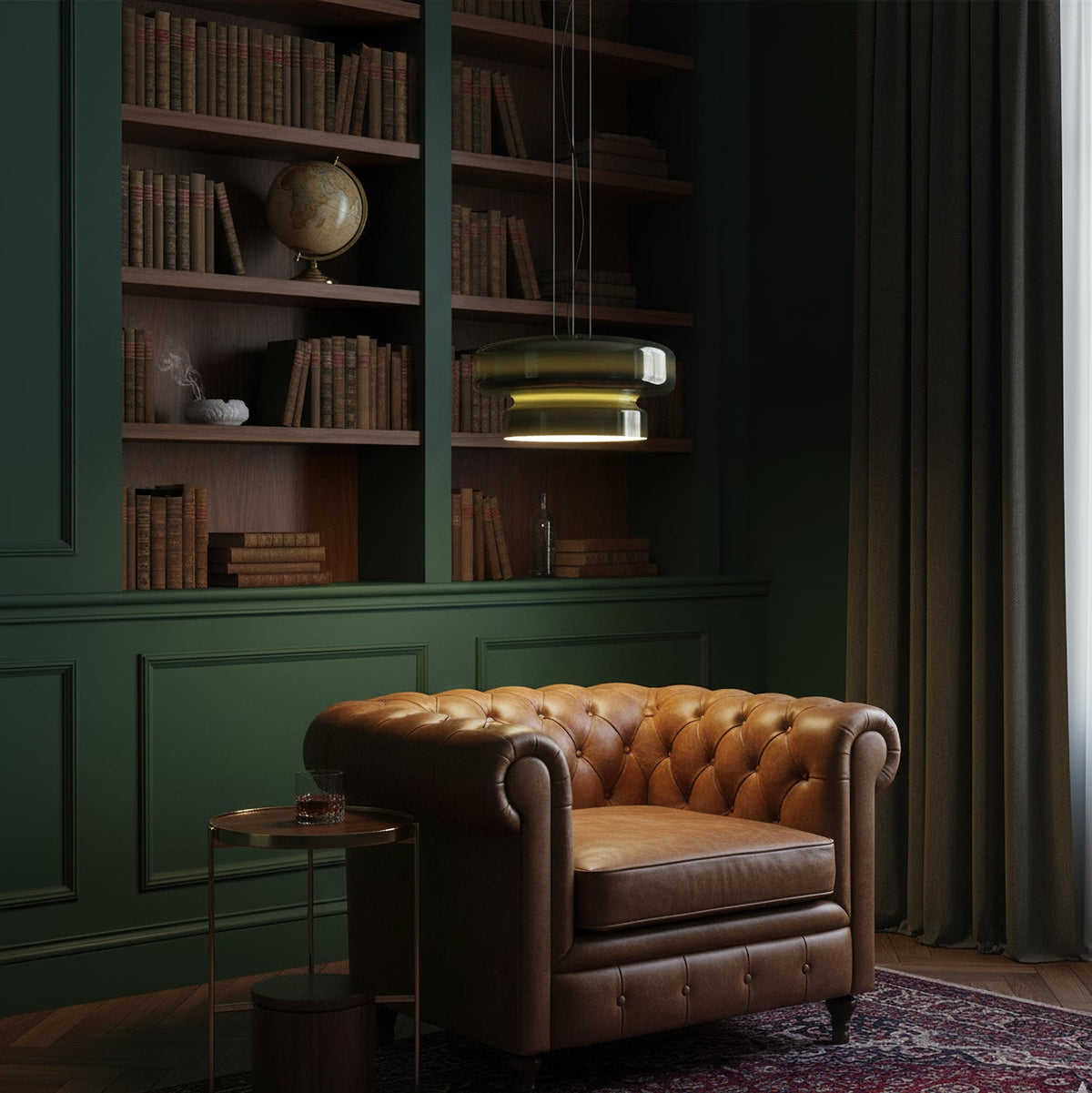 Clérachic dark green pendants glow above a leather armchair, in a dark green panelled corner with a shelf of books.