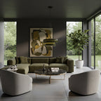A Clérachic green glass pendant hangs in a dark living room with a green sofa, a round marble-topped coffee table and a large framed print.