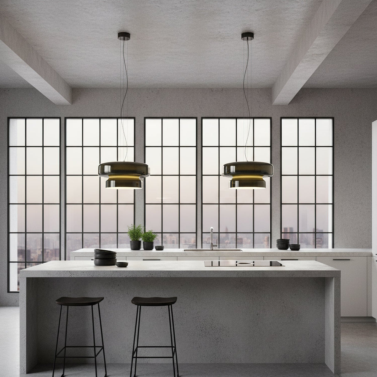 Two Clérachic dark glass pendants hang above a grey kitchen island with black stools, in front of a wall of grid-pane windows.