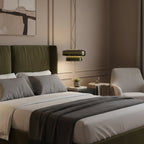 A Clérachic dark green glass pendant hangs beside a bed with a green headboard, grey bedding and a small side table.