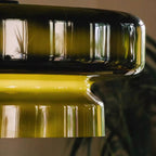 Close view of the rounded rim and the yellow-green glow at the waist of this Clérachic green glass pendant.