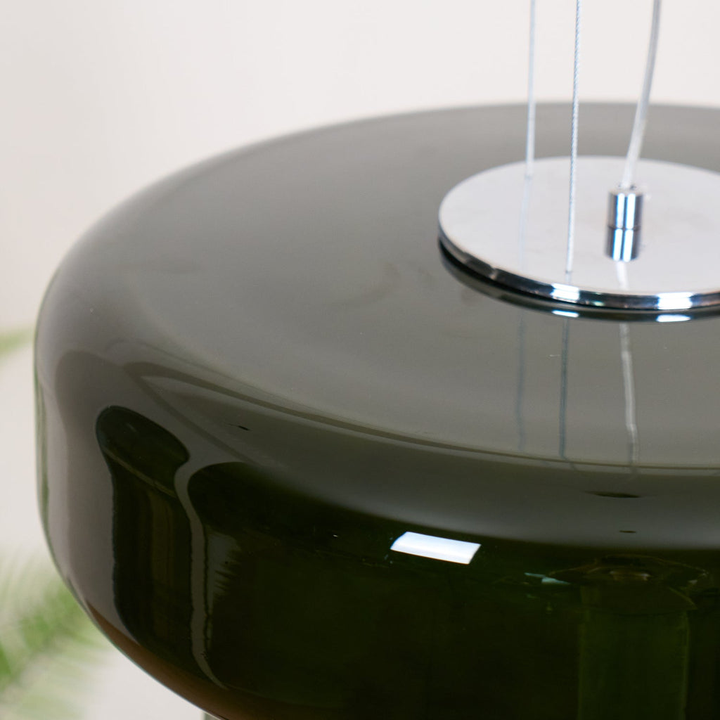 Close view of the chrome top plate and clear cords on this Clérachic dark green glass pendant.