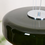 Close view of the chrome top plate and clear cords on this Clérachic dark green glass pendant.