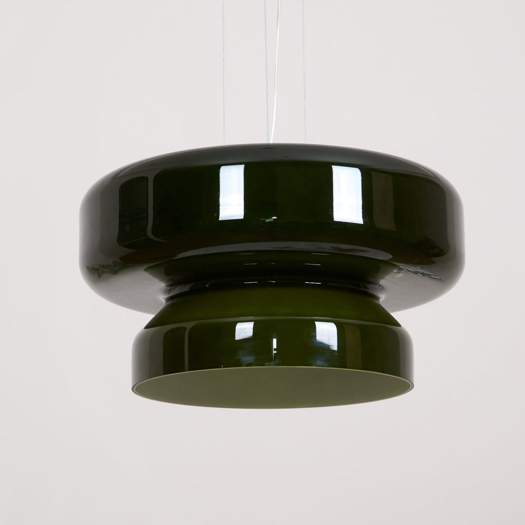 A Clérachic dark green glass pendant hung from clear cords, against a plain pale wall.