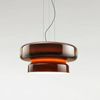 A Clérachic pendant in Amber Red glass, with a glowing orange band between its two tiers, on a pale backdrop.
