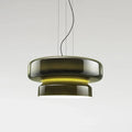 A Clérachic pendant in dark green glass, with a yellow glow between its two tiers, on a pale grey backdrop.