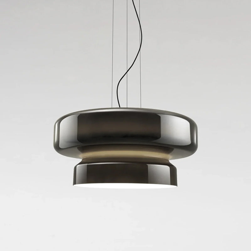 A Clérachic pendant in smoky brown-grey glass, with a soft beige glow between its two tiers, on a pale grey backdrop.