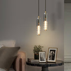 Two smoke grey glass Clérachic pendants hang at different heights above a round marble table with framed photographs.