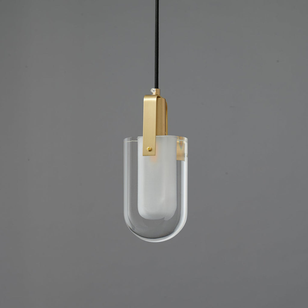 A Clérachic pendant with a U-shaped clear glass shade, a frosted inner liner and a brass bracket, unlit on a grey backdrop.