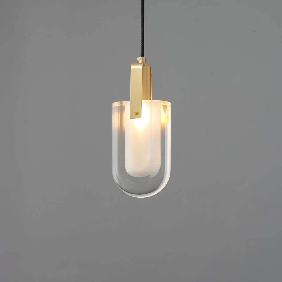 The U-shaped glass Clérachic pendant lit softly, with its frosted inner liner glowing inside the clear outer shade.