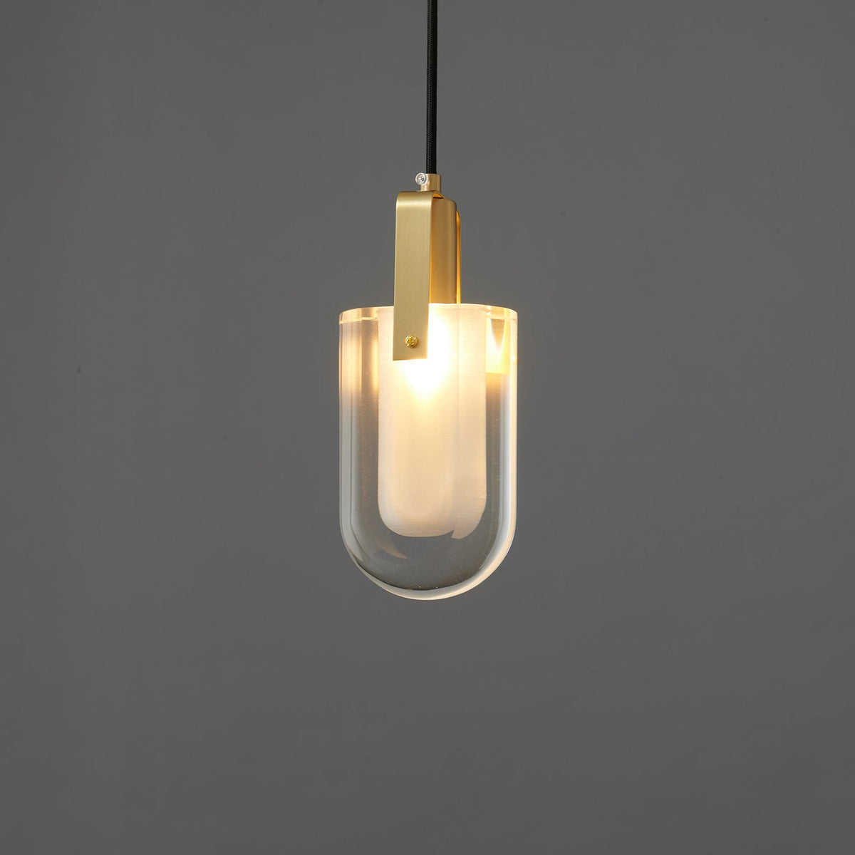 The U-shaped glass Clérachic pendant lit brighter, with a warm white glow through the frosted inner liner.