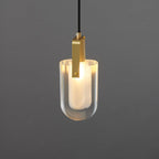 A close view of the lit U-shaped Clérachic pendant, showing the brushed brass bracket and the glow of the frosted liner.